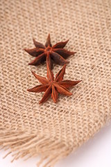 two whole star anise in closeup over jute background