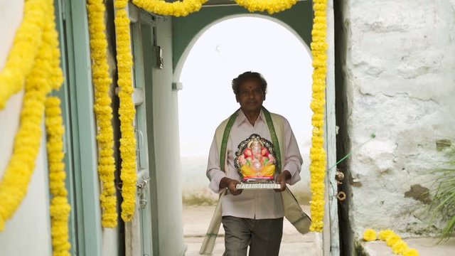happy Elder man with Ganesha Idol coming home during ganesha or vinayaka Chaturthi festival - Concept of indian religious festival celebration