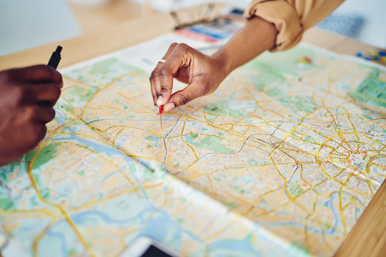 Cropped image of woman's hand pointing on mark on cartography planning adventure route on journey, top view of map of country checking direction and location for explore during travel vacation.