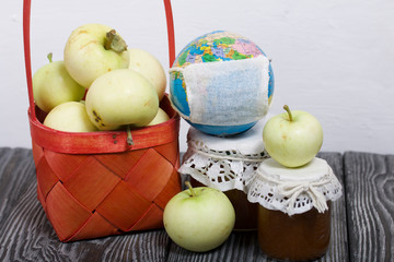 Apples in a red wicker basket. Jam in jars and apples nearby. Fruit harvest. Nearby is a globe with a medical mask.