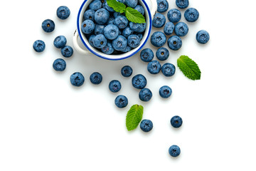 Blueberry in ceramic bowl isolated on white. Fresh blueberry closeup, healthy diet concept. Ripe organic bilberry, mint leaf creative composition. Juicy berries background, top view.