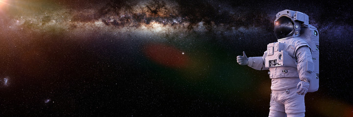 astronaut showing thumbs up during spacewalk, background banner © dottedyeti