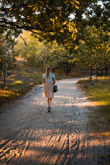 Fototapeta premium A blonde girl exploring late summer nature with golden sunset