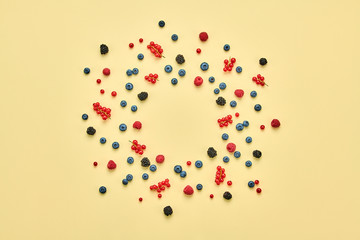 Blueberry, raspberry, blackberry, redcurrant. Fresh blueberry, berries mix closeup. Red raspberry, mint creative composition on yellow. Colorful trendy concept, top view.