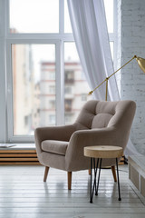 1 beige armchair in a bright room with a window background