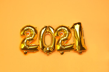 Happy New year 2021 celebration. Gold and silver foil balloons numeral 2021 on a yellow background. Postcards and posters. High quality photo. Copy space