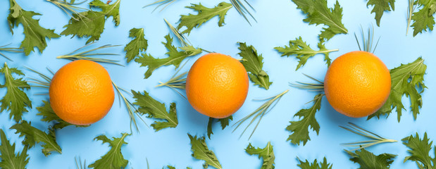 Close up of citrus fruits orange on green rucola salad leaves pattern on blue backround.