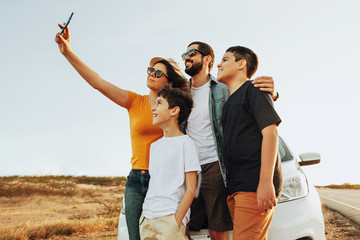 Family road trip. Latin family traveling locally by car. Taking self portrait on smartphone