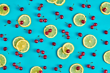 Red cherry, lemon colorful pattern on blue background. Fresh berry closeup, organic cherry wallpaper, top view. Lemonade creative concept, fashionable trendy summer beverage, flat lay