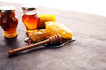 Honey in jar with honey dipper on vintage rustic background