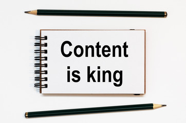 WHITE SPIRAL NOTEBOOK, TWO PENCILS WITH TEXT CONTENT IS KING