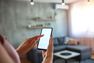 Mobile Phone With Home Control System On A white screen. Woman controlling light with a smart phone at home.  Concept of a smart home and light control with mobile devices