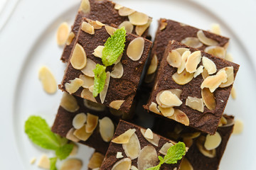 Squares Chocolate brownie with almond sliced set on white cafe table.