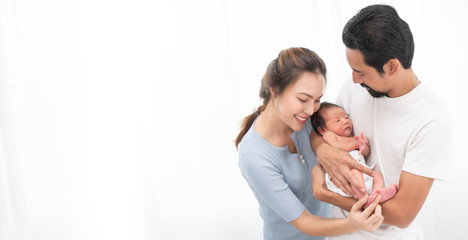 Smiling asian mother and father holding their newborn baby son at home. Proud asia mother and father with daughter infant on white background banner. © sutlafk