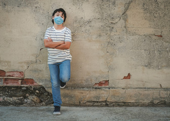Fototapeta na wymiar happy kid wearing medical mask leaning against a wall