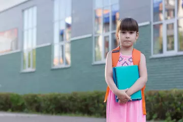 Fotobehang Schattig klein schoolmeisje met rugzak met notitieboekjes op het erf © Albert Ziganshin