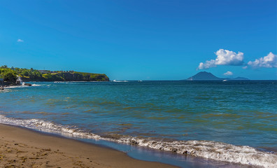 A view along a tranquil beach in St Kitts with the island of Sint Eustatius in the distance