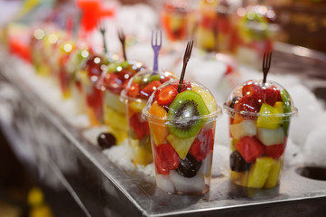 Plastic cups with fresh different fruits on the market.