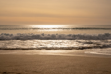 Playa al atardecer en hora dorada. Pequeñas olas en playa de Galicia