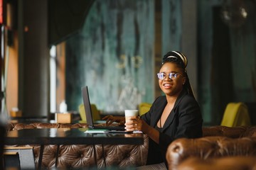 Portrait of a young black woman smiling and using laptop
