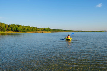 Fototapeta na wymiar Clean lake Svityaz, Ukraine. Sandy bottom of the lake. In the distance a man in a yellow kayak. Copy space.