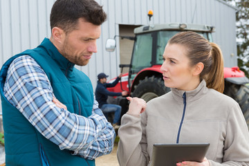 farmer and woman with clipboard talking on dairy farm