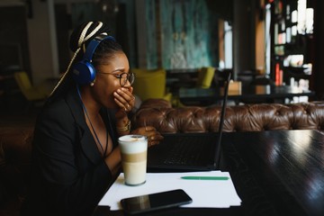 Young African American woman siting at cafe working on laptop