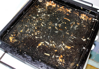 Soaked greasy baking sheet on the stove filled with water before washing.