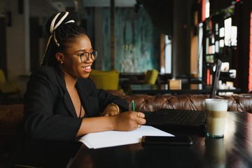 Young African American woman siting at cafe working on laptop