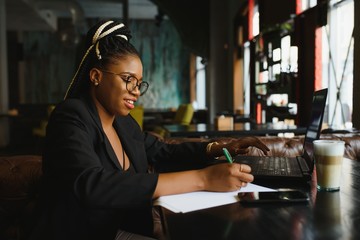 Young African American woman siting at cafe working on laptop