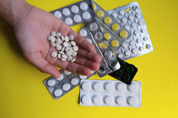 Pills of various medicines, tablets on a yellow background. Healthcare. View from above. Copy space. Pharmaceutical picture. Pills in hand
