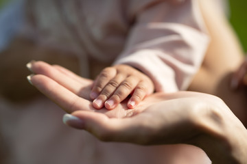 child's hand rests on mother's palm, selective focus