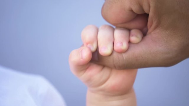 A kid hand holds the father's finger. Raising children in the family, taking care of children. Close-up of a kid's hand. Concept of family planning. A newborn child holds his father's hand.