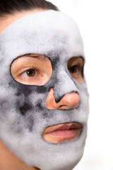 Isolated girl with charcoal cleansing mask on the face.