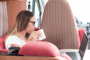 Mujer de mediana edad con gafas teletrabajando con su ordenador portátil en vacaciones desde su...