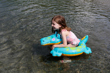 happy laughing girl enjoying swimming in sea with rubber ring crocodile