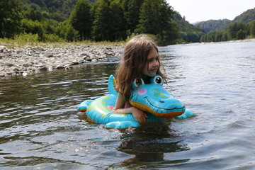 happy laughing girl enjoying swimming in river with rubber ring crocodile