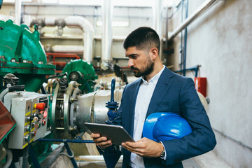 businessman holding tablet computer in industry plant