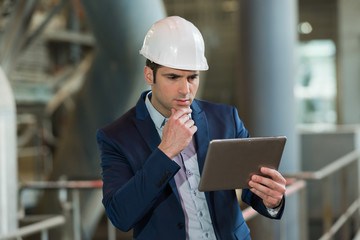 businessman holding tablet in factory