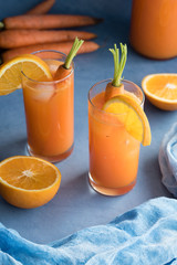 Fresh orange and carrot juice on blue background.
