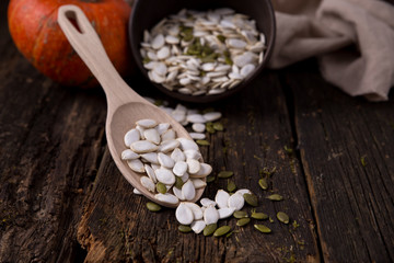 White and green pumpkin seeds on a spoon and in a bowl Horizontal composition with pumpkin. Background image. close plan