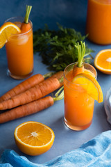 Fresh orange and carrot juice on blue background.