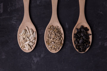 Sunflower seeds are black and white. mockup on three spoons top view on dark background 