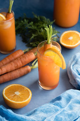 Fresh orange and carrot juice on blue background.