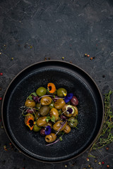 different types of olives on a dark concrete