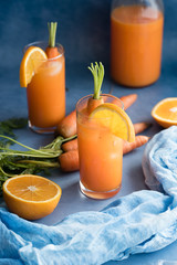 Fresh orange and carrot juice on blue background.