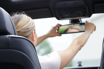 woman driving adjusting rear view mirror