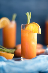 Fresh orange and carrot juice on blue background.