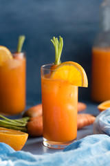 Fresh orange and carrot juice on blue background.