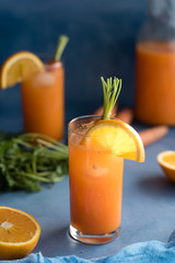 Fresh orange and carrot juice on blue background.